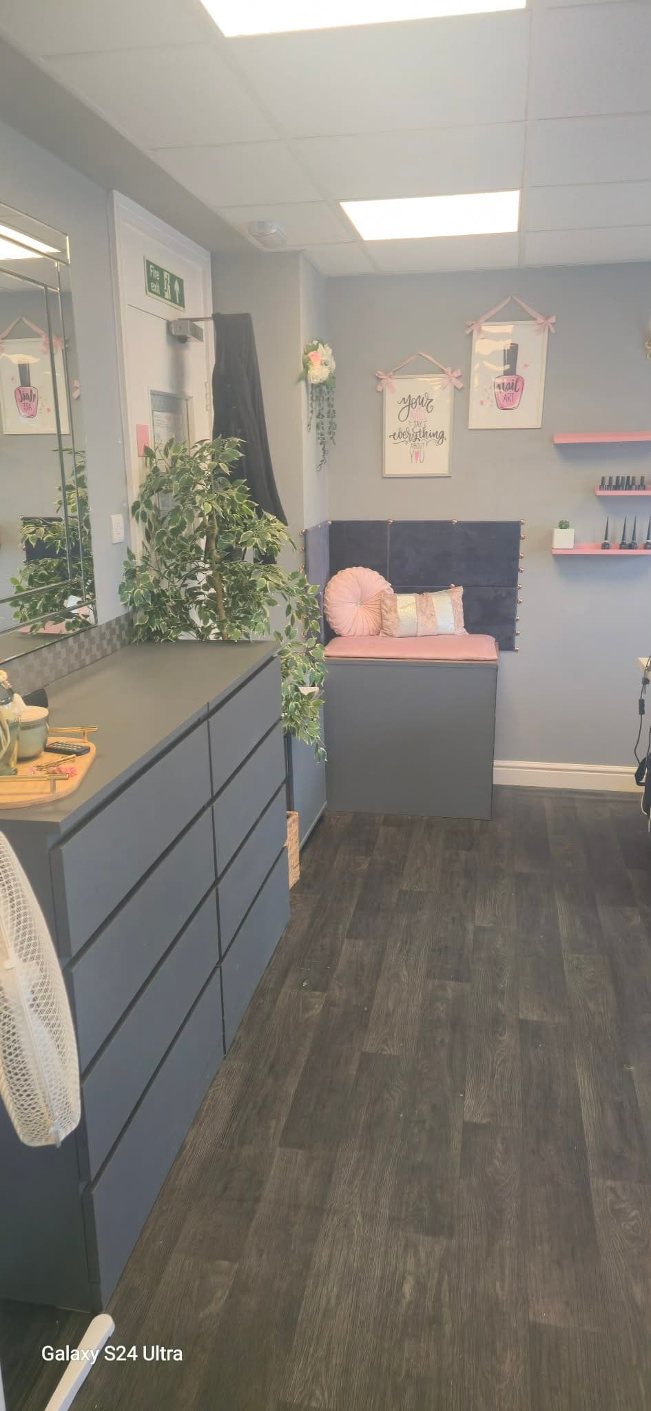 Salon storage, mirrors and pink client seating in the nail area